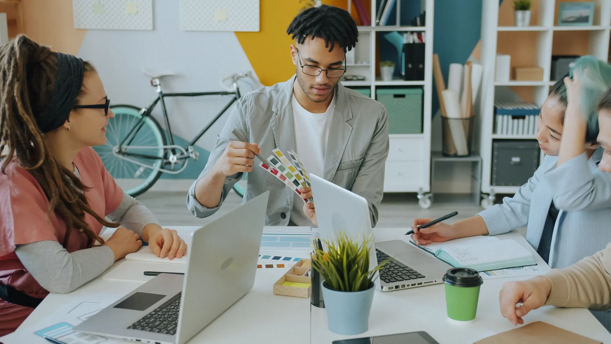 A design team reviewing colour swatches around a table of laptops